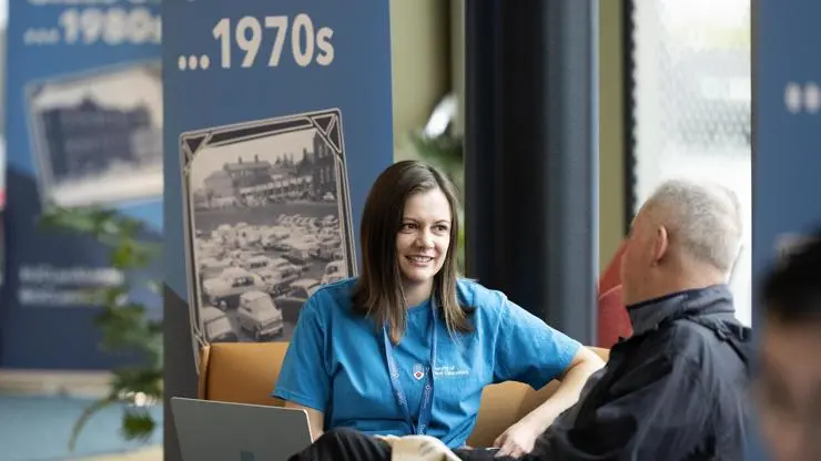 A member of UCLan staff chatting with a graduate from the 1970s