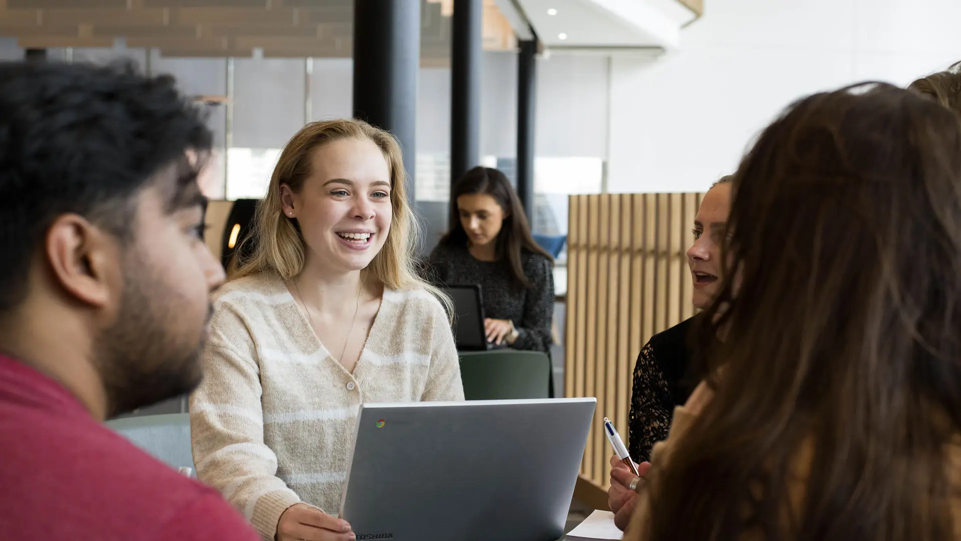 students sat in a group chatting with a laptop