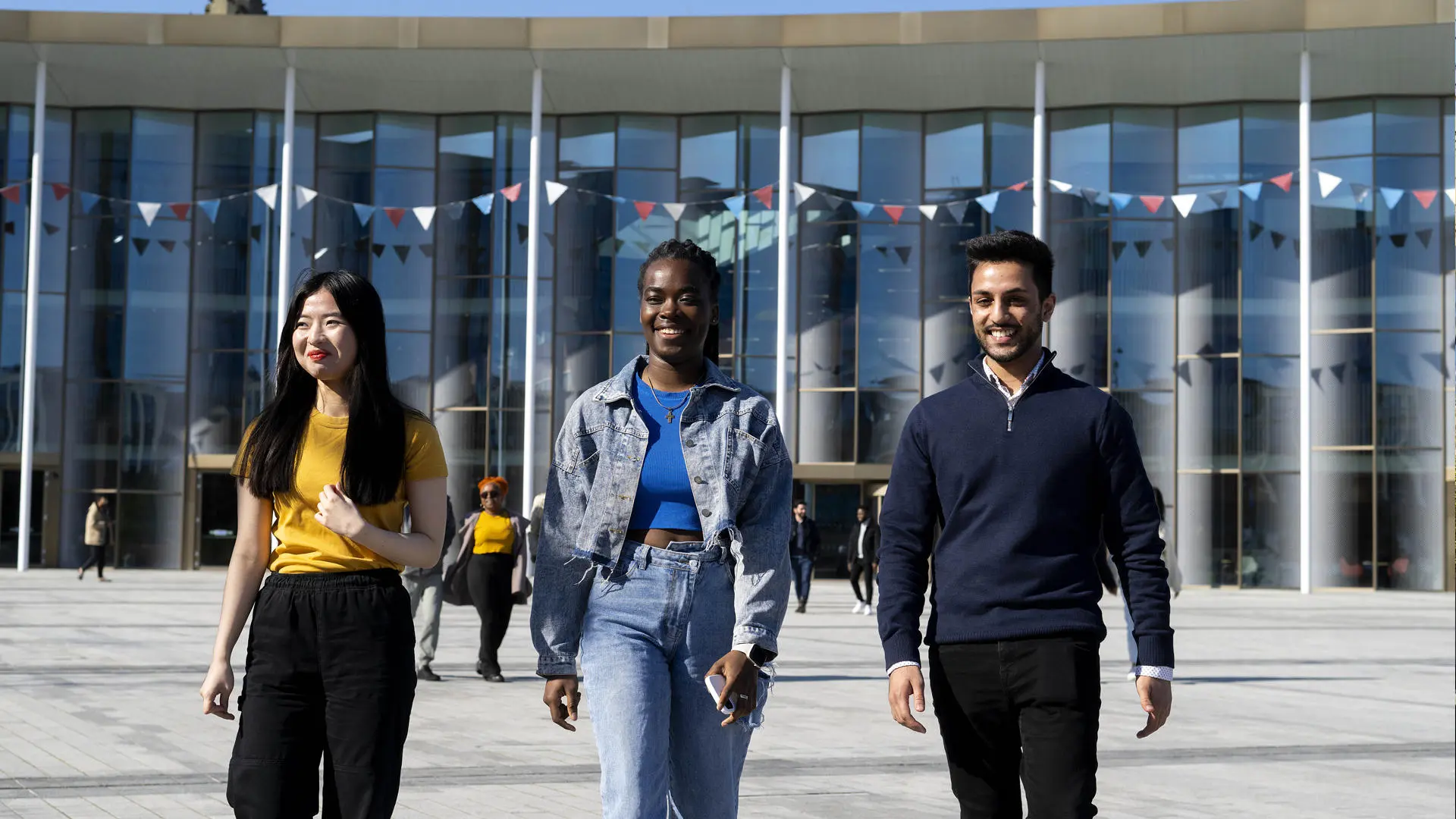 three students walking in a row outside of the student centre