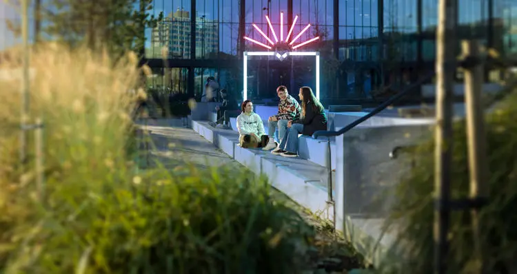 group of students sat on steps outside the eic decorative shield added to background